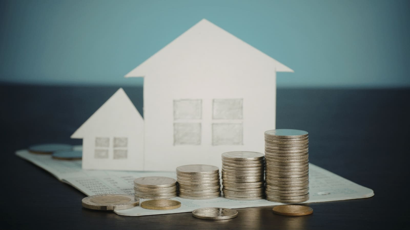 Paper cut out of houses with coin stacks